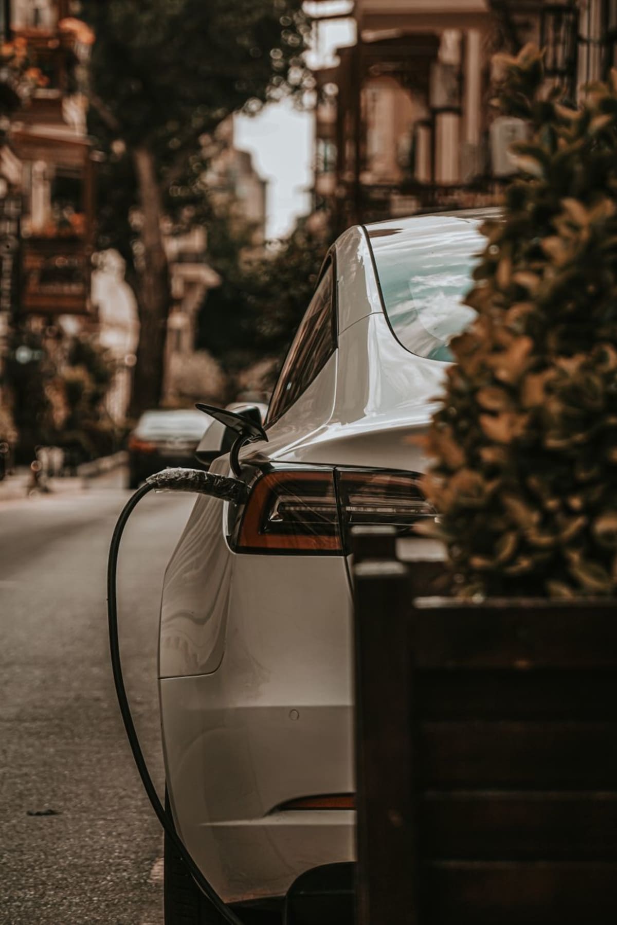 Modern electric vehicle charging at home station with solar panels visible on house roof