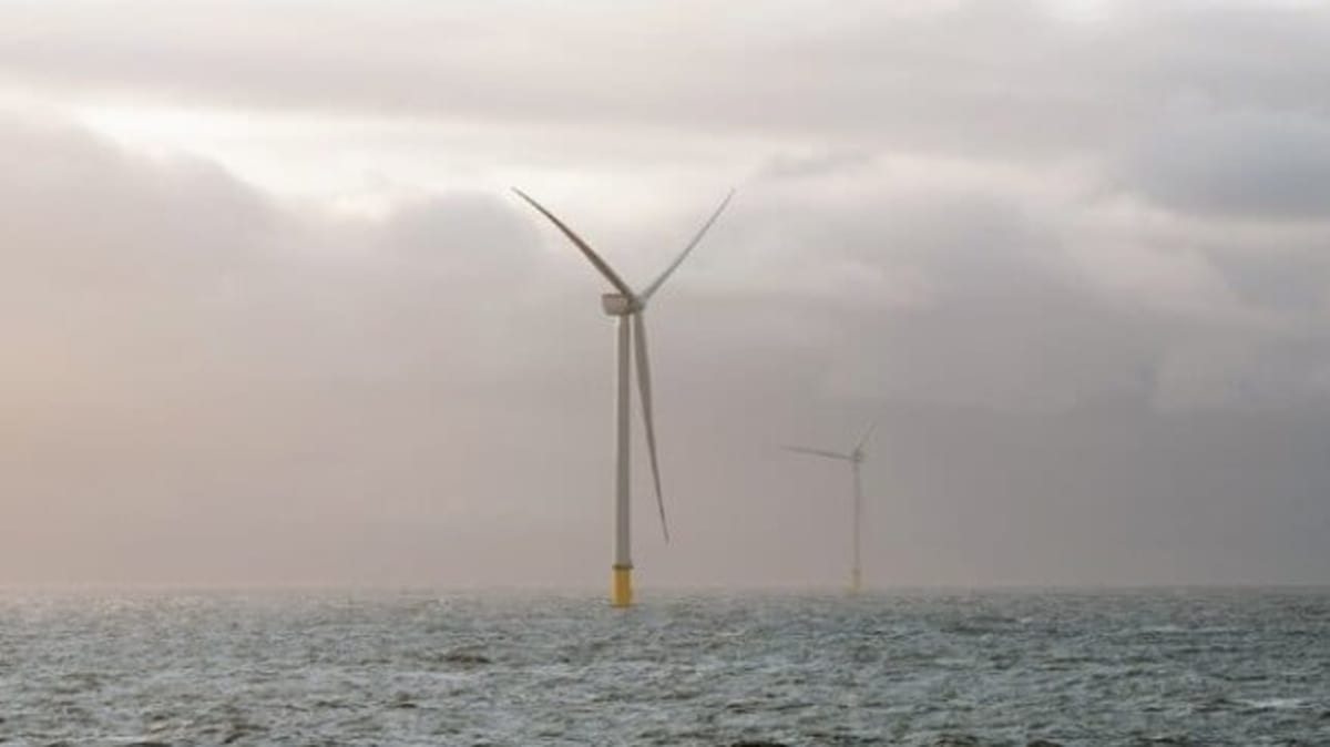 Offshore wind turbines rising from ocean waters off the UK coast generating renewable electricity