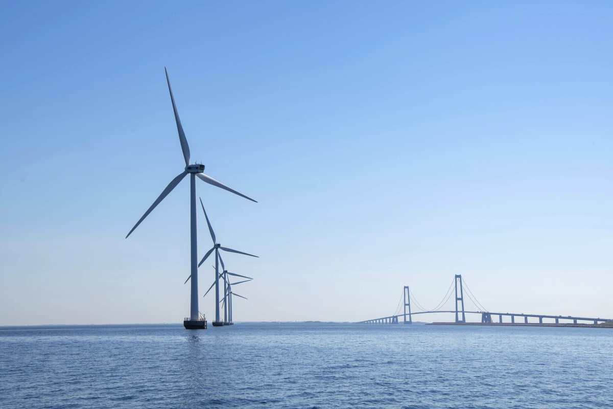 Offshore wind turbines rising from ocean waters under clear blue sky in Denmark