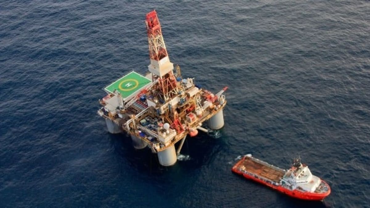 Offshore supply vessel operating in Norwegian waters near oil platform under clear skies