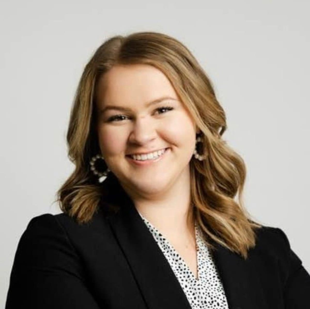 Young woman student holding books on agricultural college campus with sunshine and green fields