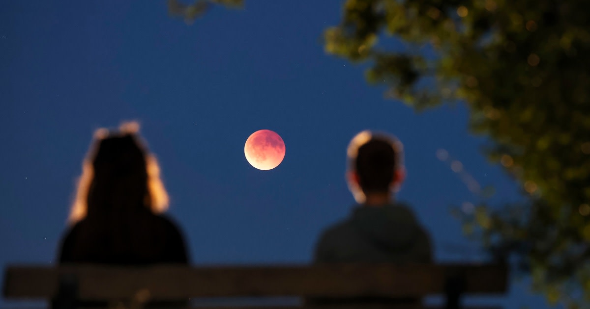 Reddish-orange moon during near-total lunar eclipse as Earth's shadow covers lunar surface