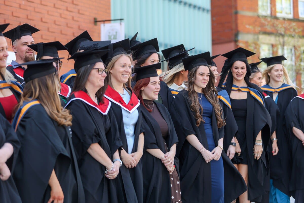 Graduates in academic regalia celebrating at Cambria University Centre ceremony in Wrexham, Wales