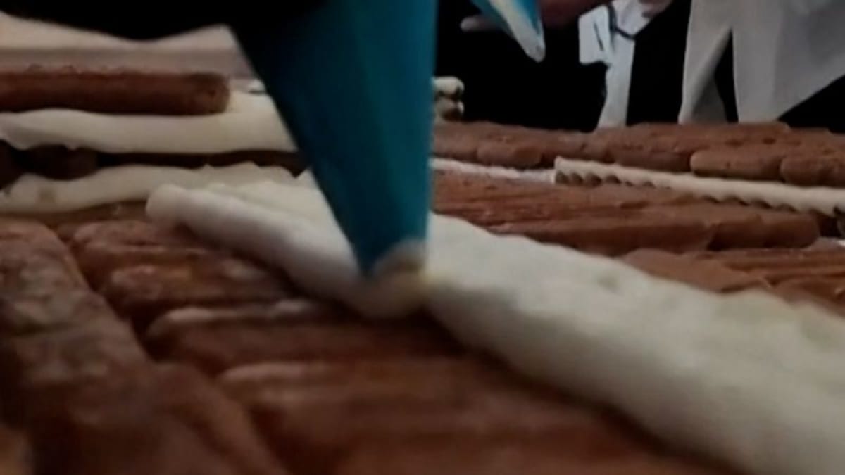 Aerial view of extremely long tiramisu dessert stretching across London venue with chefs standing alongside