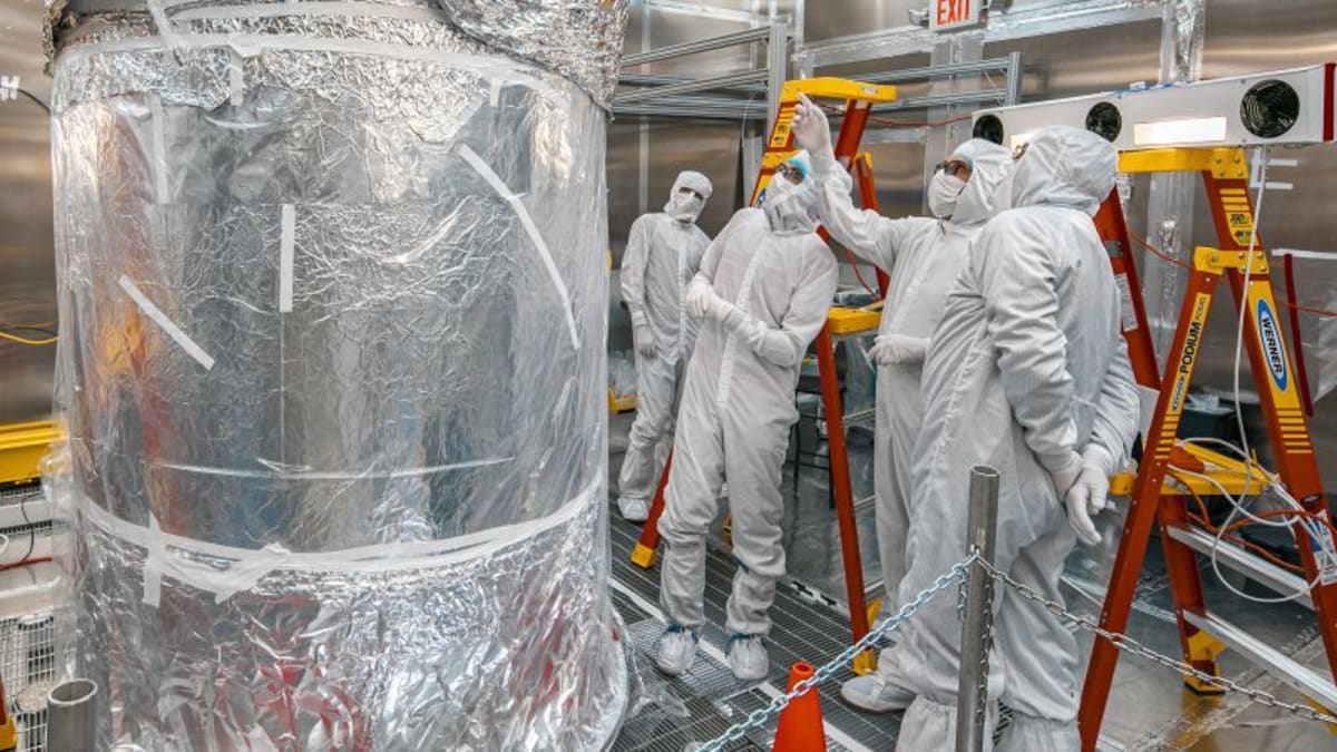 Scientists examining large cylindrical detector filled with liquid xenon in underground laboratory