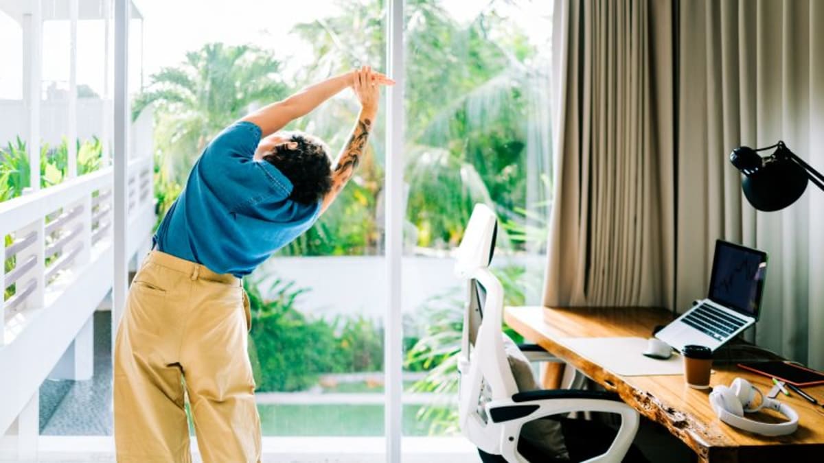 Person taking a standing stretch break from desk work in modern office space