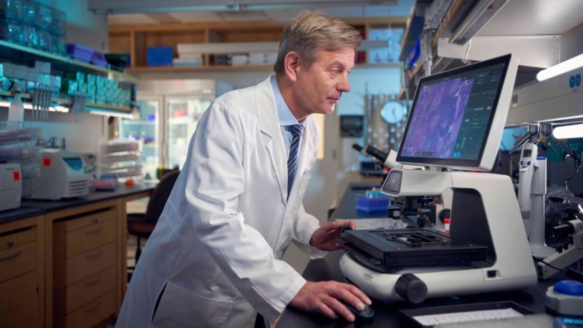 Cancer researcher in white coat examining probiotic capsules in modern laboratory setting
