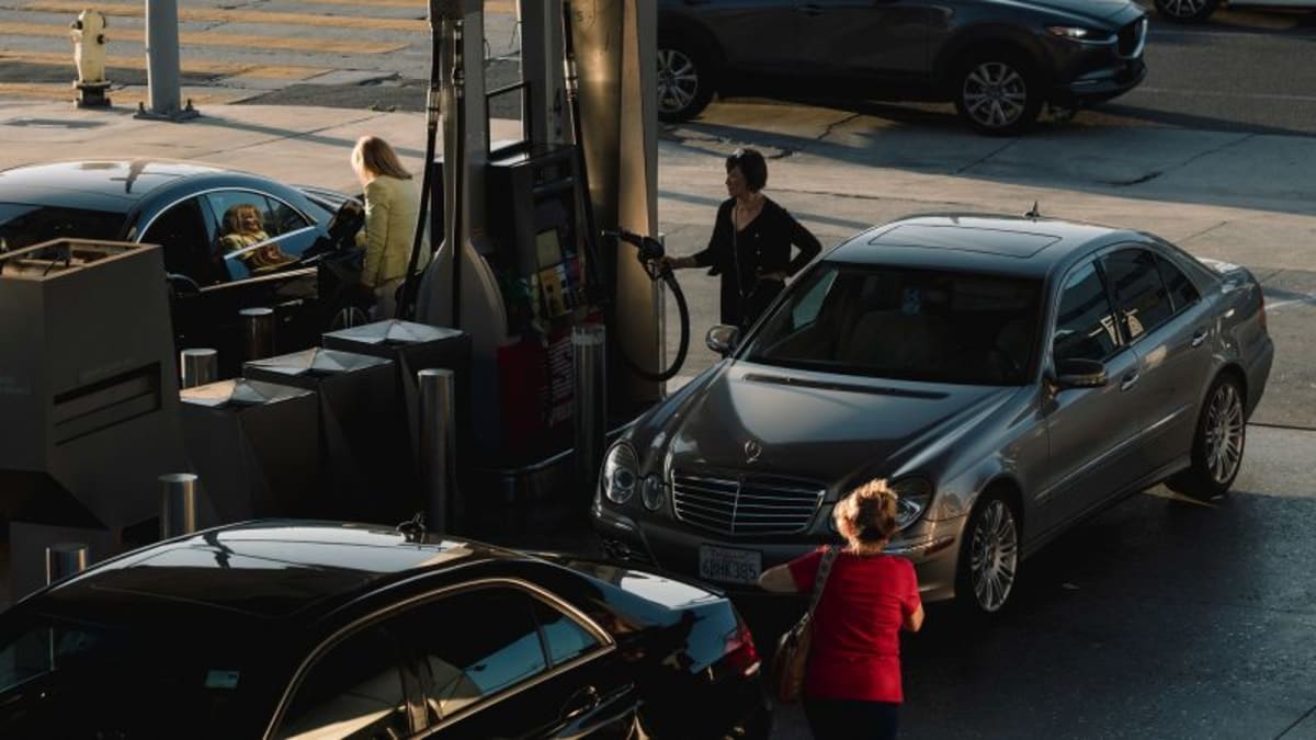 Driver pumping gas at station as fuel prices drop across America