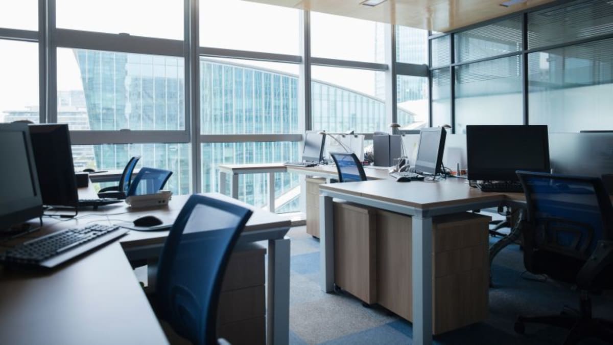 Modern office workspace with computer screens showing AI tools and collaborative work environment
