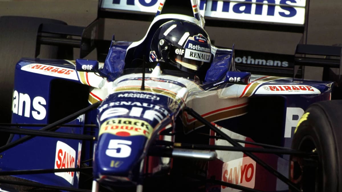 ** Damon Hill sitting in restored blue Williams FW18 Formula 1 race car at Goodwood Festival