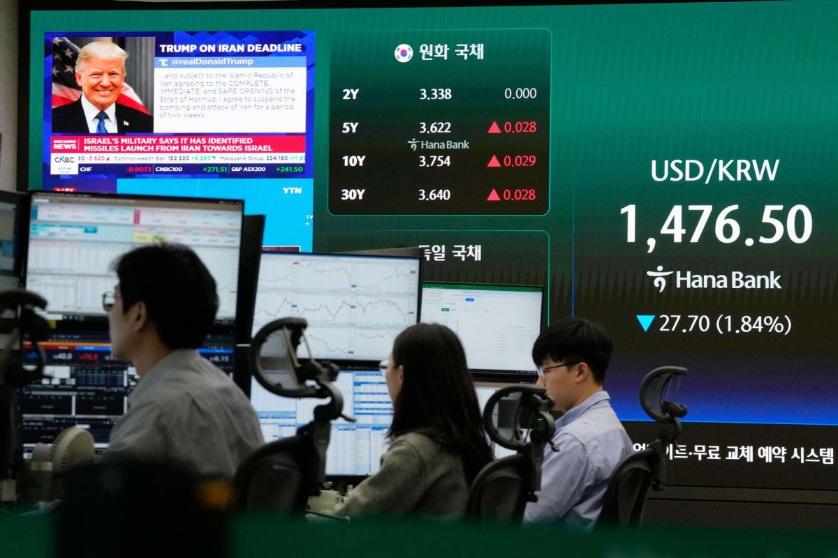 Currency traders monitor screens showing rising Asian stock market charts in Seoul trading room
