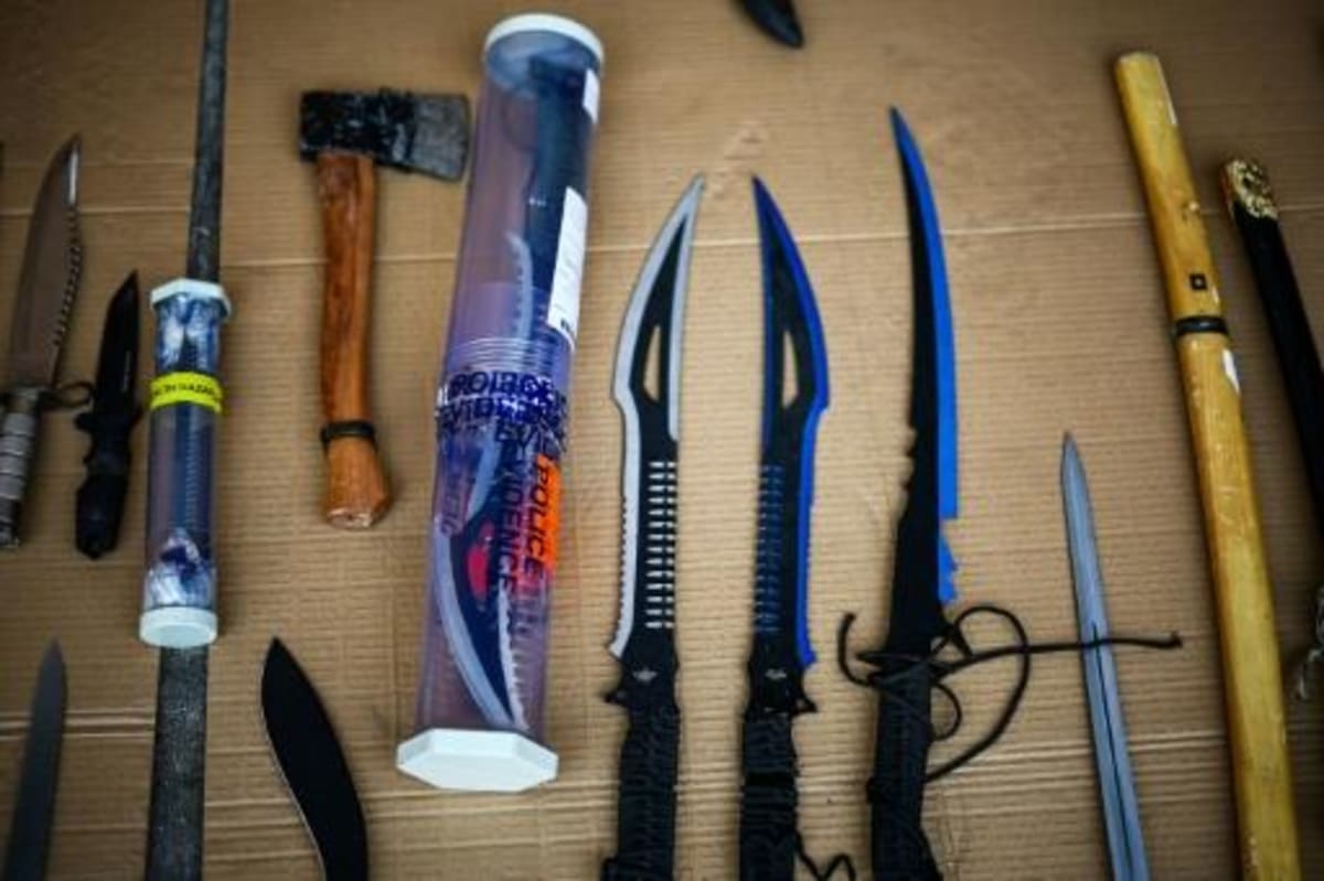 Array of confiscated knives and machetes displayed on table during police training event