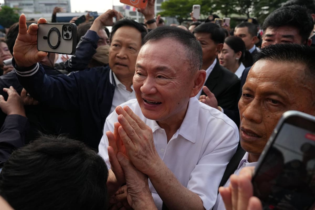 Thaksin Shinawatra in white polo shirt greeting supporters outside Bangkok prison