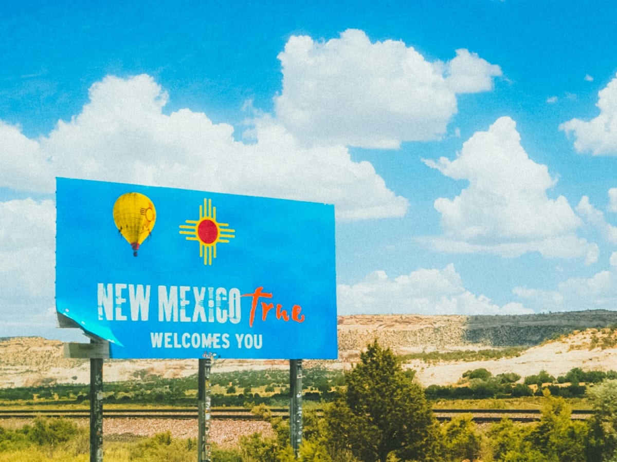 Wind turbines spinning across New Mexico desert landscape under bright blue sky