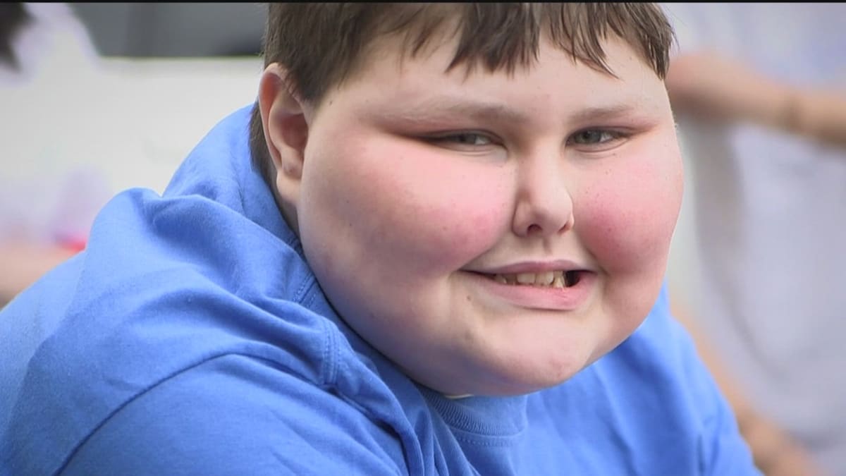 Teen cancer survivor Jude Baker smiling while helping distribute meals and supplies to community members