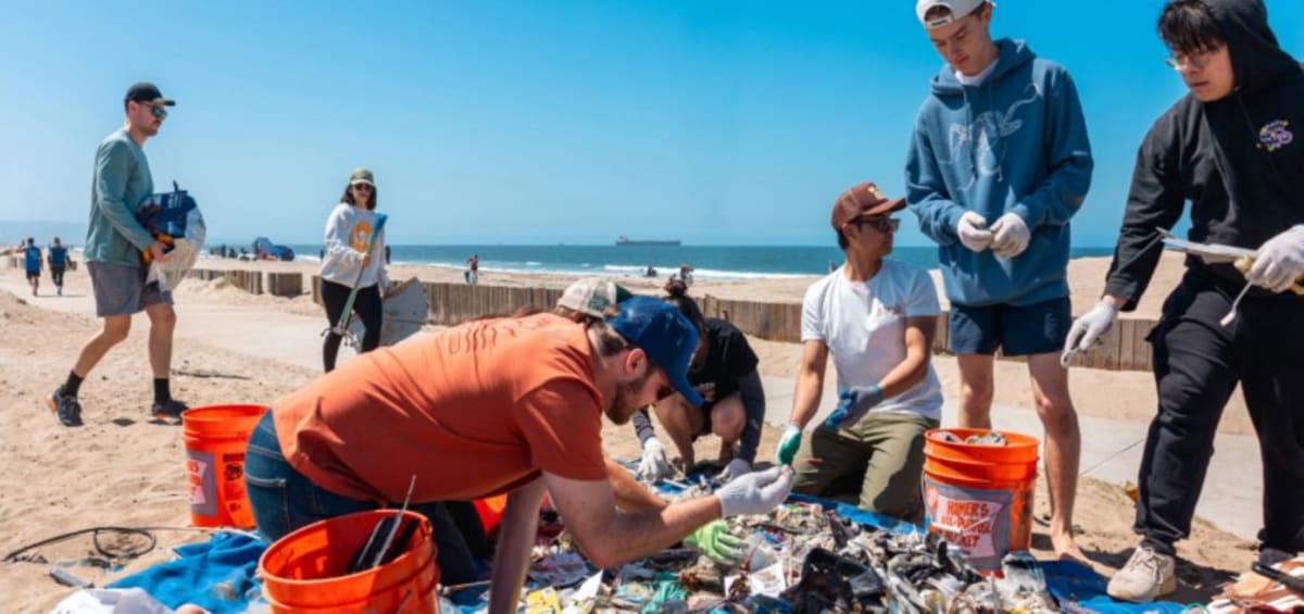 ** Volunteers including children collect trash and debris during a Surfrider Foundation beach cleanup on Kauai