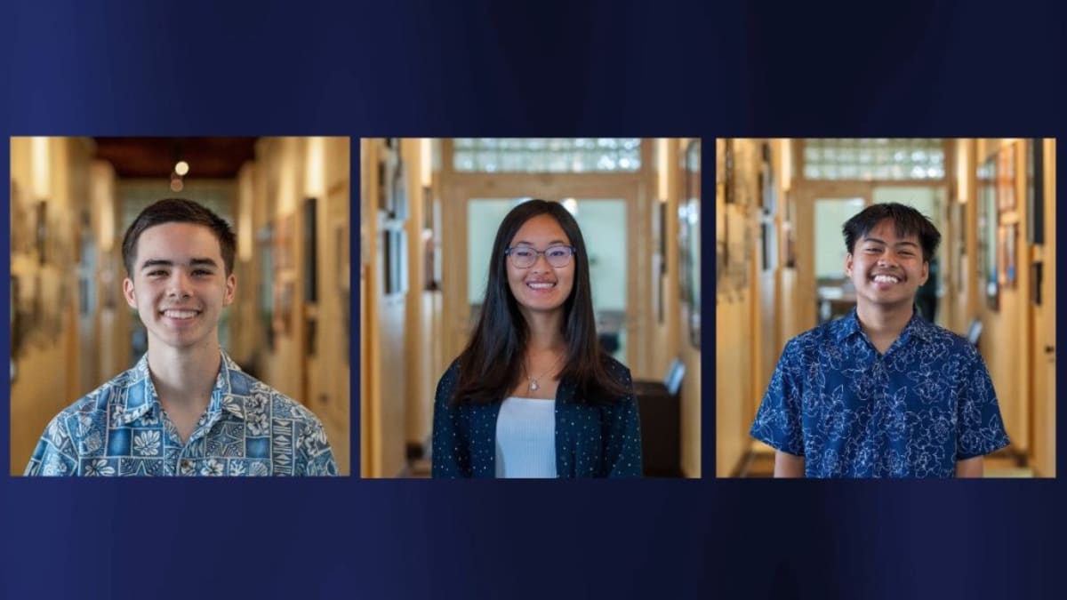 Three smiling Kauaʻi high school students in graduation attire holding scholarship award certificates
