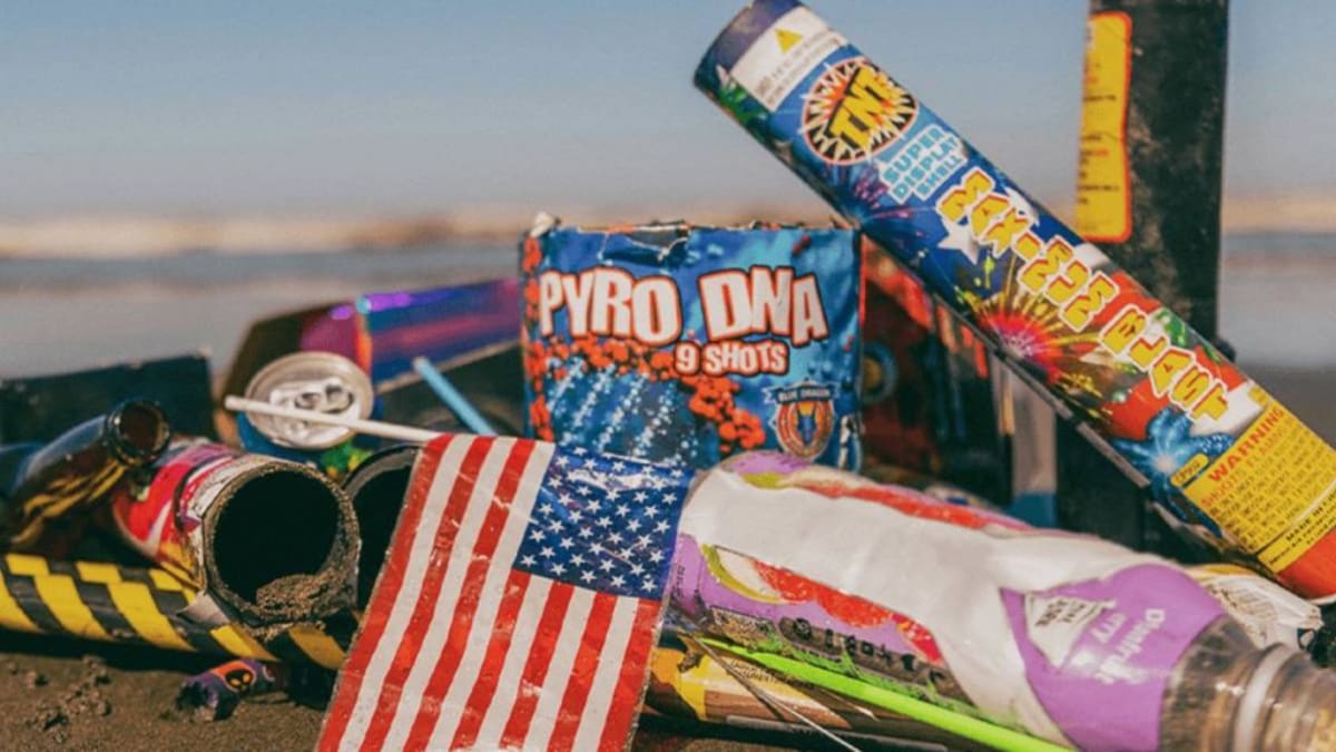 Volunteers in gloves collecting trash and debris scattered across sandy beach after July Fourth