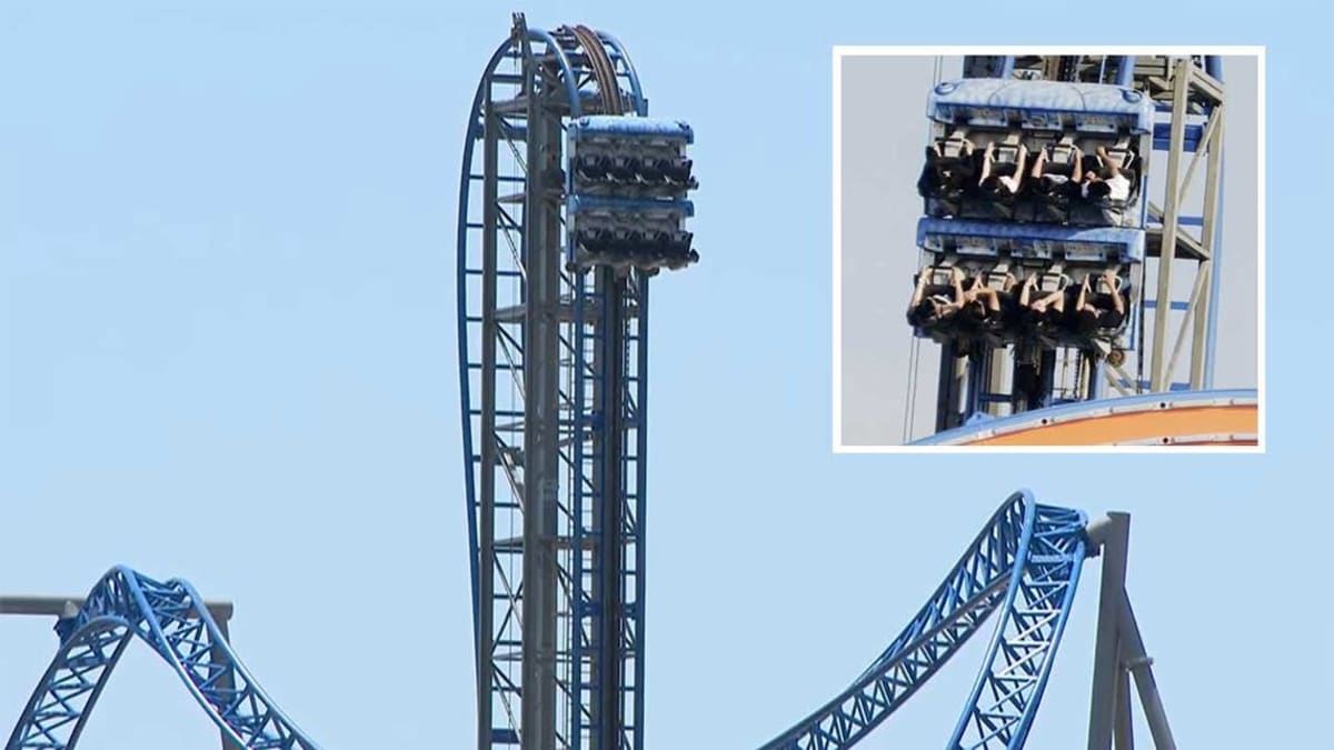 Firefighters in ladder truck bucket rescue student from stopped roller coaster high above pier
