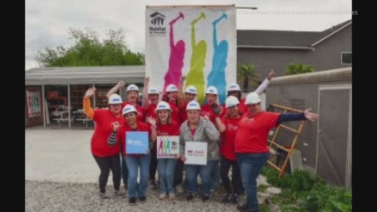 Women volunteers wearing hard hats and safety vests working together on home construction site
