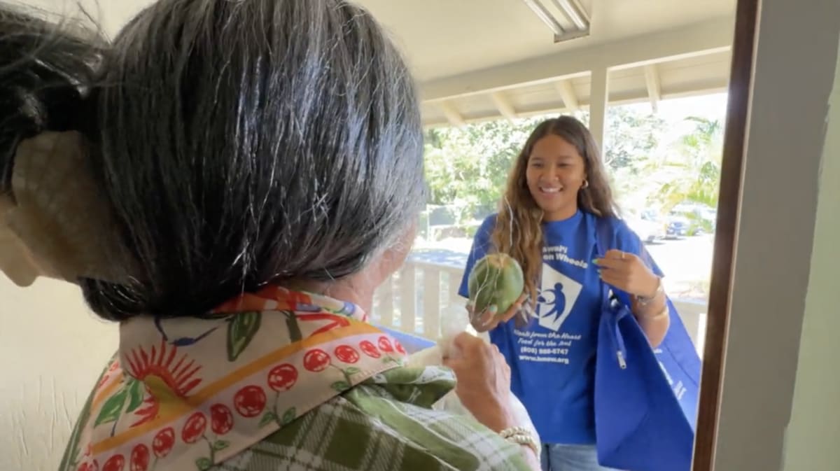 Volunteer delivering a nutritious meal to a senior at their home in Hawaii