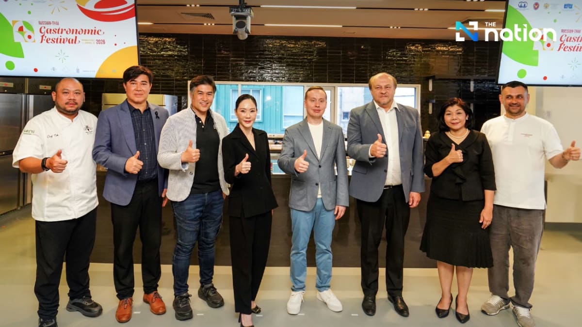 Russian and Thai chefs collaborating in kitchen creating fusion dishes at Bangkok food festival