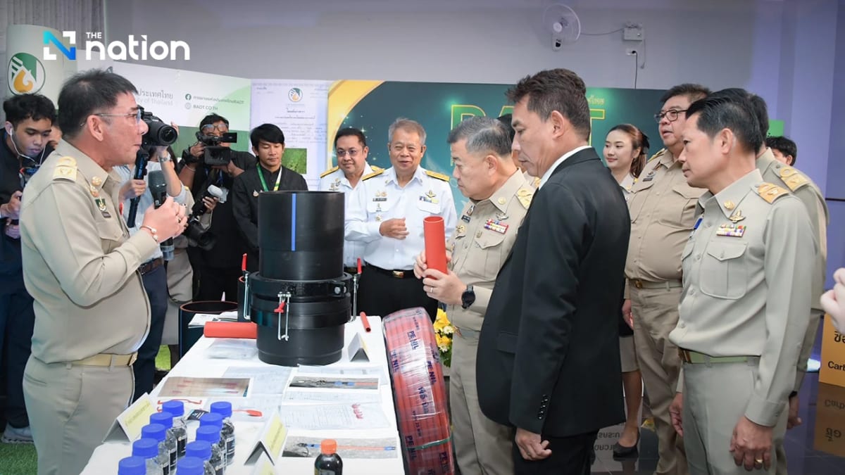 Workers installing rubber-blended irrigation pipes in Thai agricultural fields with water canals