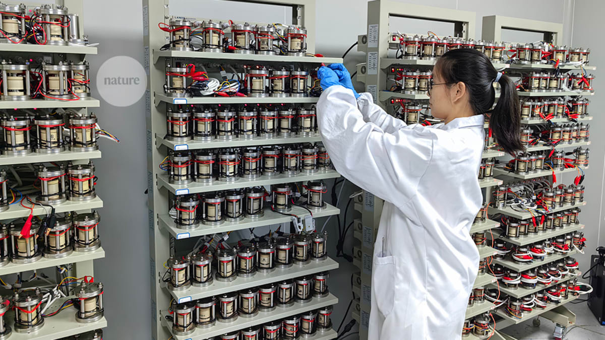 ** Female scientist in laboratory examining solid-state battery materials for safer energy storage research