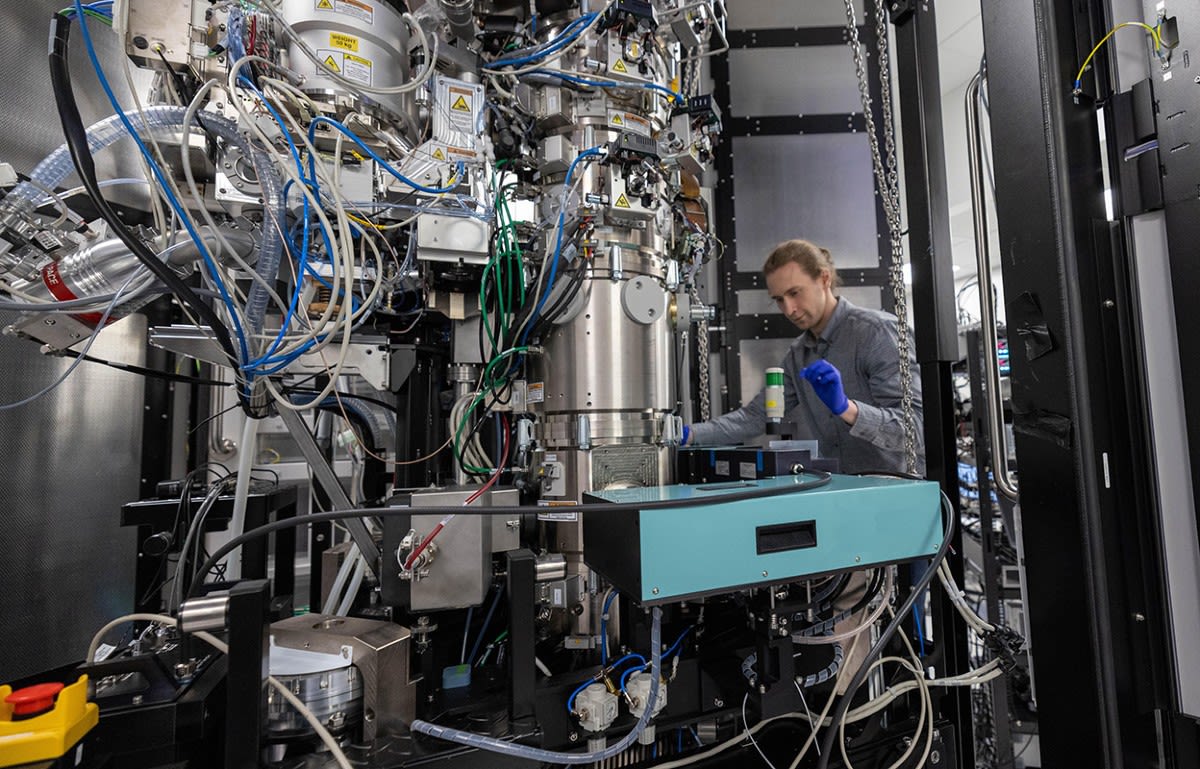 Scientist adjusting laser equipment inside cryo-electron microscope at California research facility