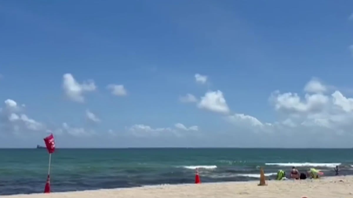 Lifeguard watching ocean through binoculars from elevated beach patrol station in South Florida