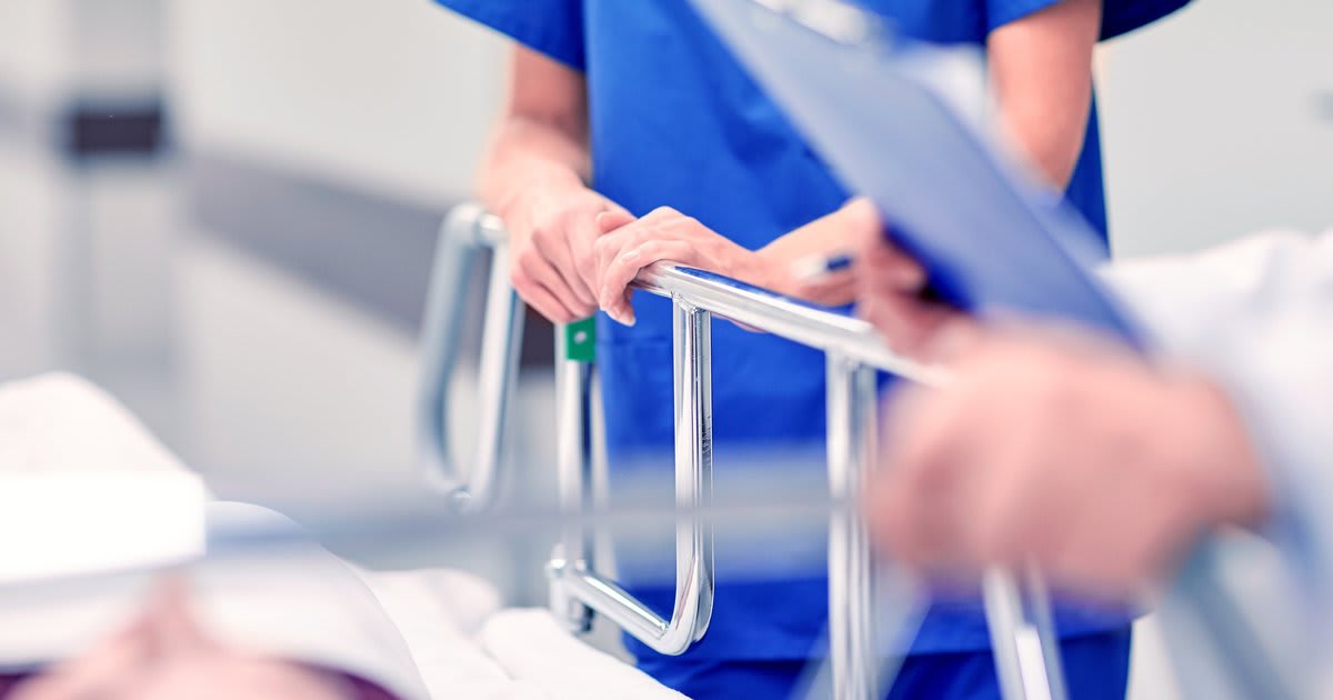 Hospital nurse caring for patient in bed with medical equipment nearby