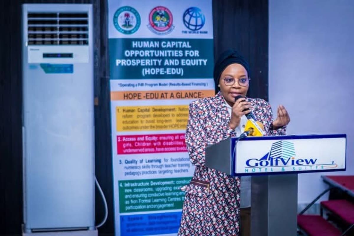 Nigerian students sitting in a bright classroom raising hands to answer questions