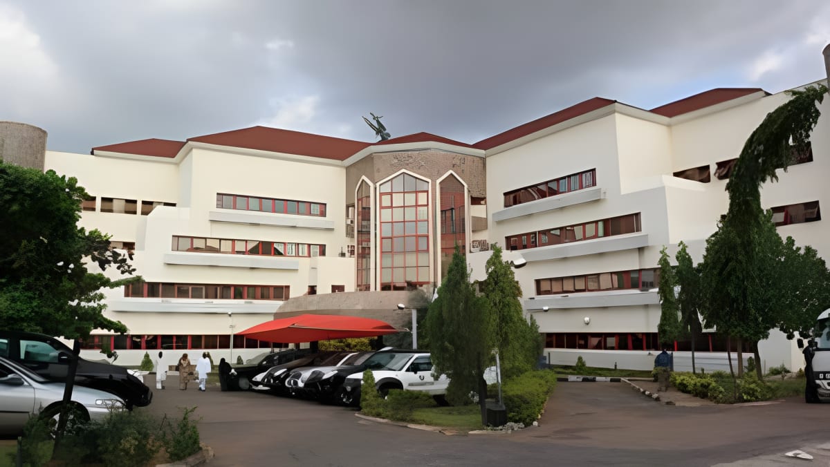 Nigerian students in classroom raising hands eagerly to participate in lesson