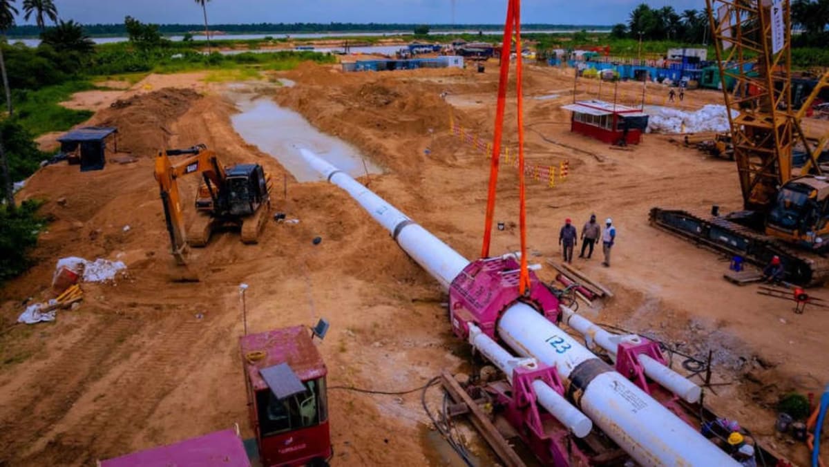 Industrial pipeline construction equipment at River Niger crossing site in Nigeria's Niger Delta region