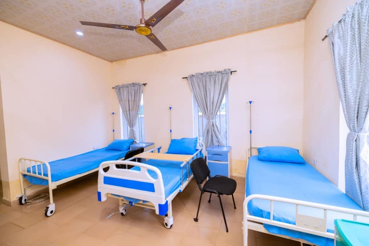 ** Healthcare workers assisting mothers and children at a modern primary health center in Enugu State, Nigeria