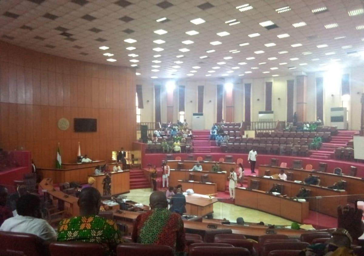 Flooded corridor inside abandoned Nigerian legislative building with damaged roof and standing water