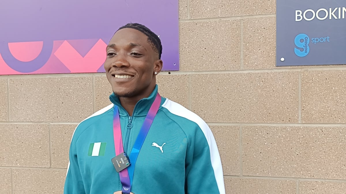Young Nigerian sprinter Kayinsola Ajayi smiling while holding his Commonwealth Games bronze medal in Glasgow