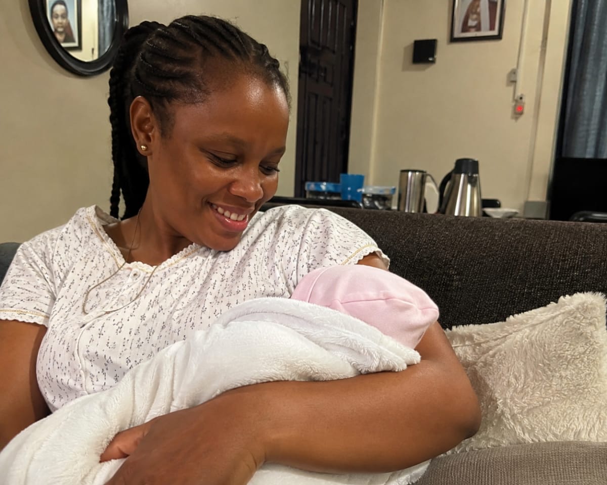 Nigerian midwife teaching new mother proper newborn care techniques in hospital setting