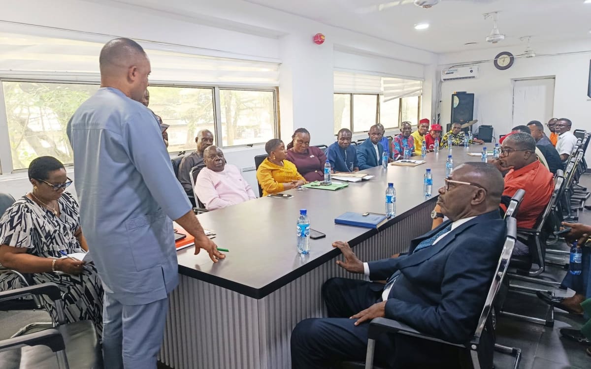 Government officials and community representatives gathered around conference table for peaceful land dispute mediation in Nigeria