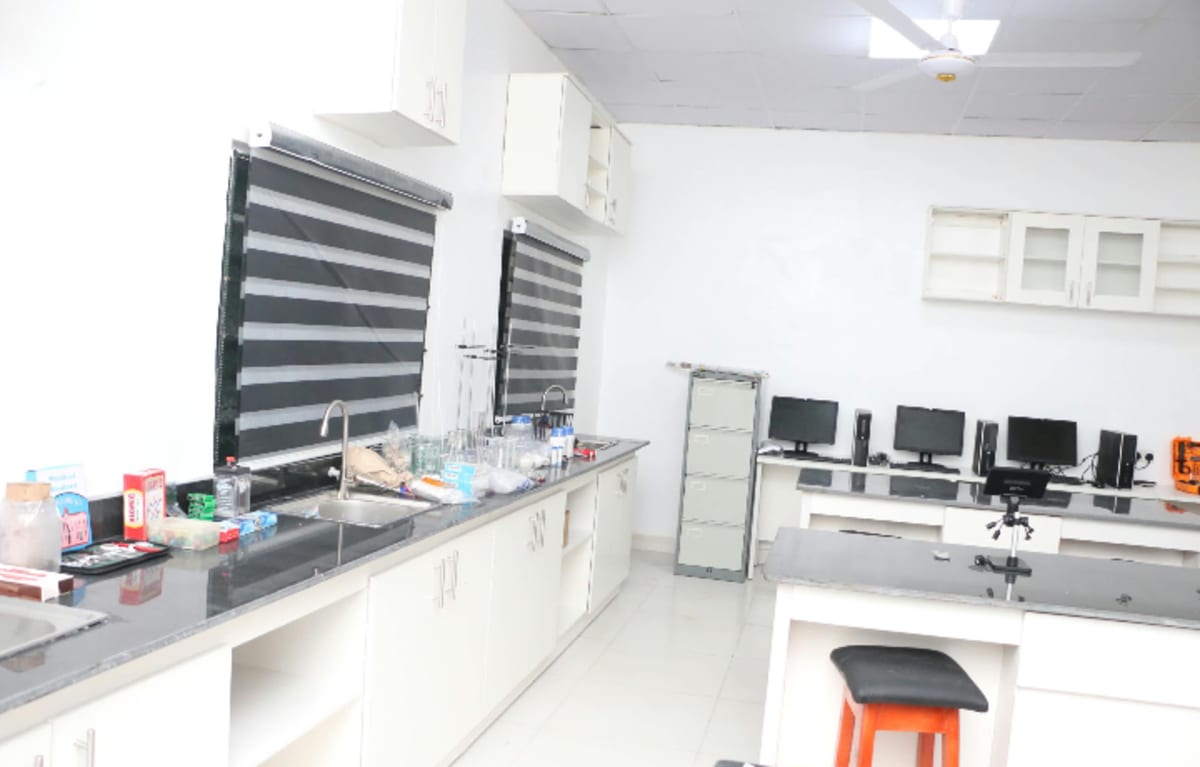 Nigerian students in white uniforms working with scientific equipment in modern STEAM laboratory