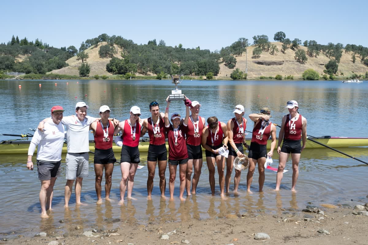Harvard lightweight rowing team celebrates with championship trophy after winning third consecutive national title