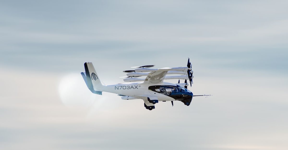 Modern electric vertical takeoff aircraft flying above urban cityscape at sunset
