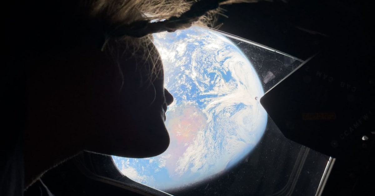 Astronaut Christina Koch looking at Earth through Orion spacecraft window during Artemis II mission