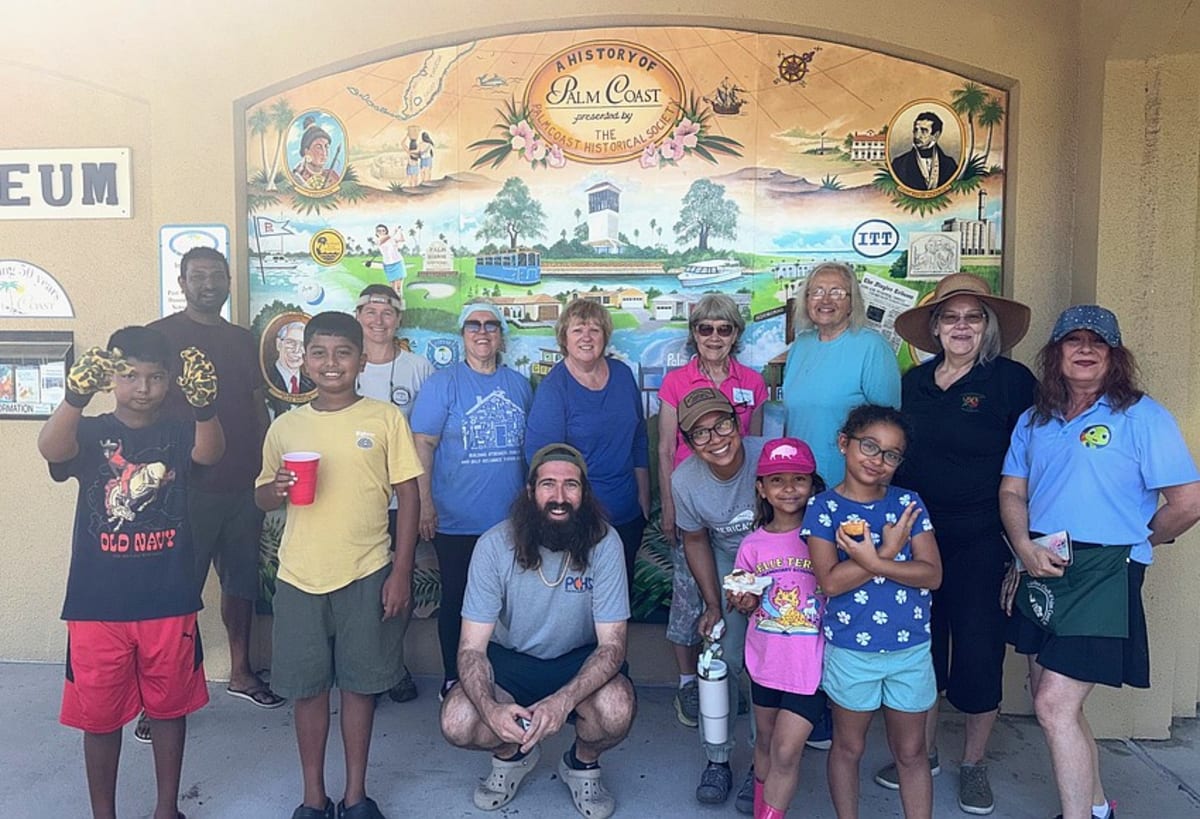 Young volunteers and adults planting native flowers in garden bed at Palm Coast museum