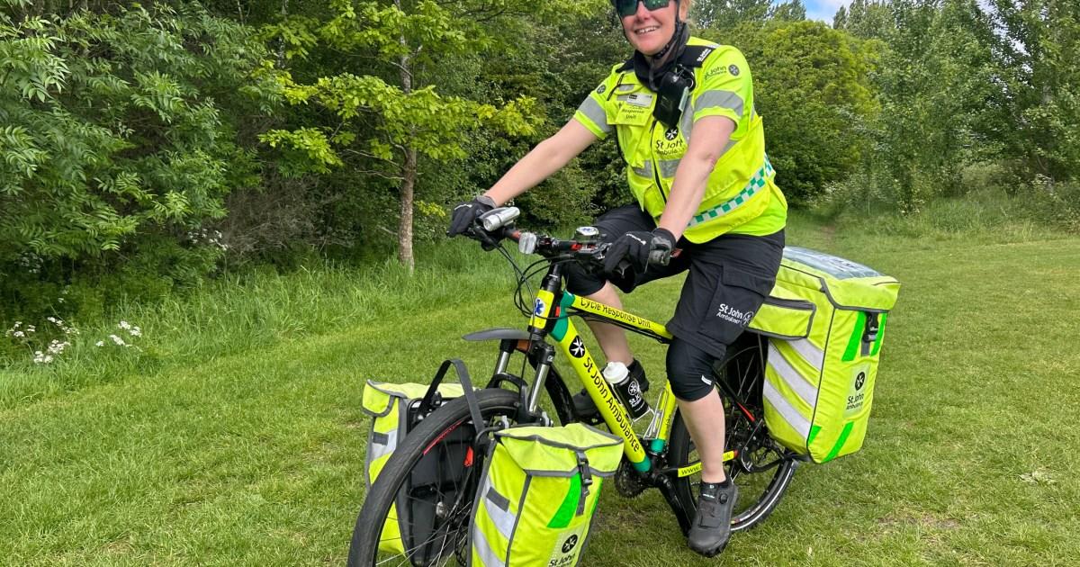 Female cycle responder volunteer in uniform on bicycle with medical equipment at crowded London public event