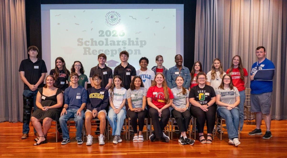** Students celebrating scholarship awards with hands raised in joy and excitement together