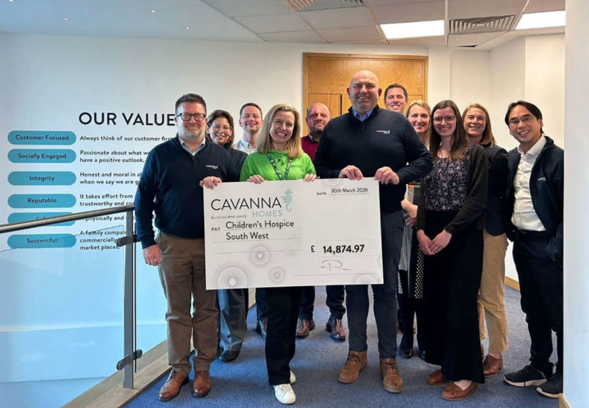 Housebuilder employees presenting oversized check to children's hospice charity representatives smiling together