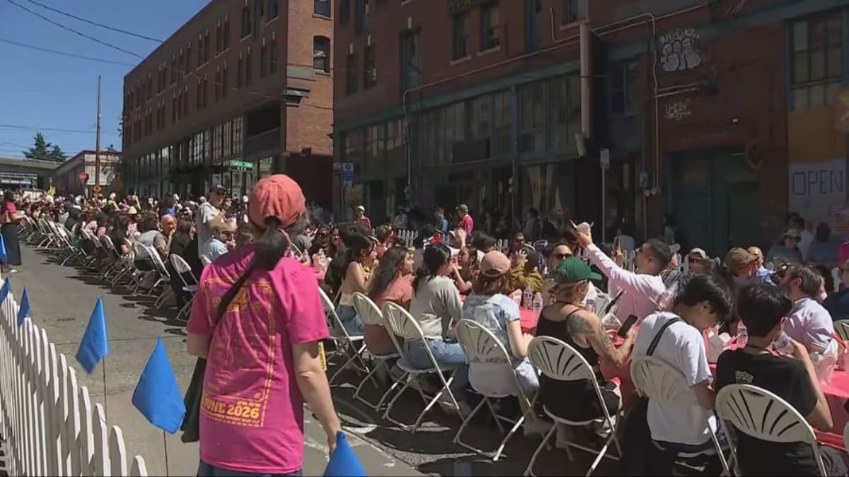 Hundreds of people seated at long tables on Seattle street enjoying dim sum together