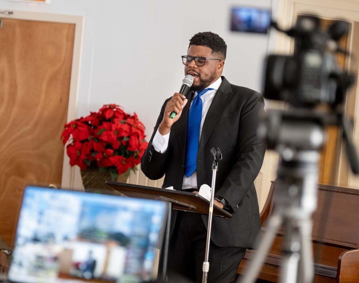 ** Reverend Damien Reese singing at church service, Hamilton family reunion organizer