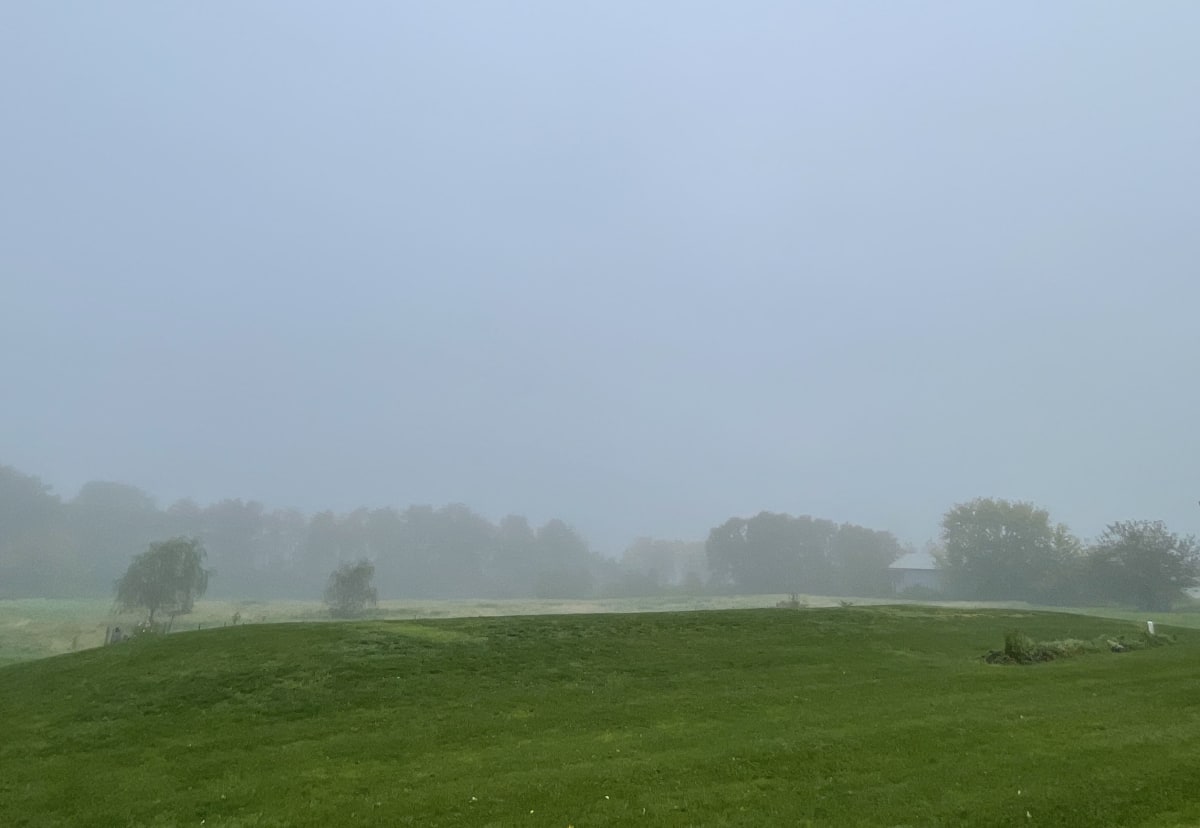 Researcher collects fog samples in misty Pennsylvania field before sunrise using collection equipment